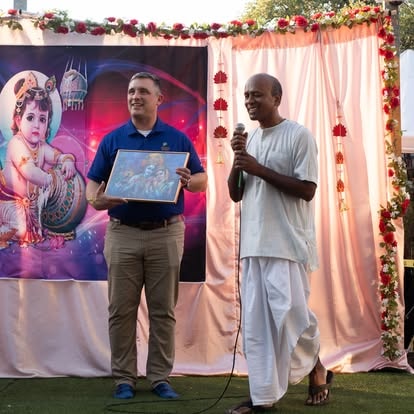 Two men presenting artwork at festive event at ISKCON Cedar Park