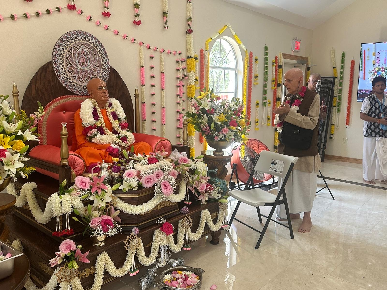 Srila Prabhupada deity honored with flower garlands as devotees gather during the temple inauguration